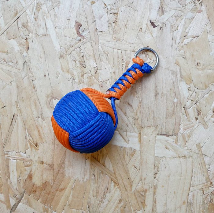 Blue and orange paracord monkey fist keyring on a workbench